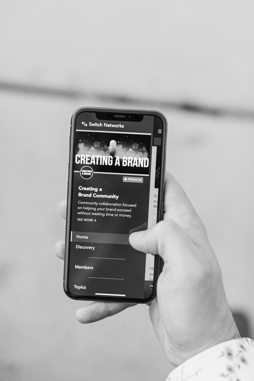 Black and white photo of a man holding an iPhone 11 Pro, using social media. Learn more about the model, Alex Sanfilippo @ PodPros.com